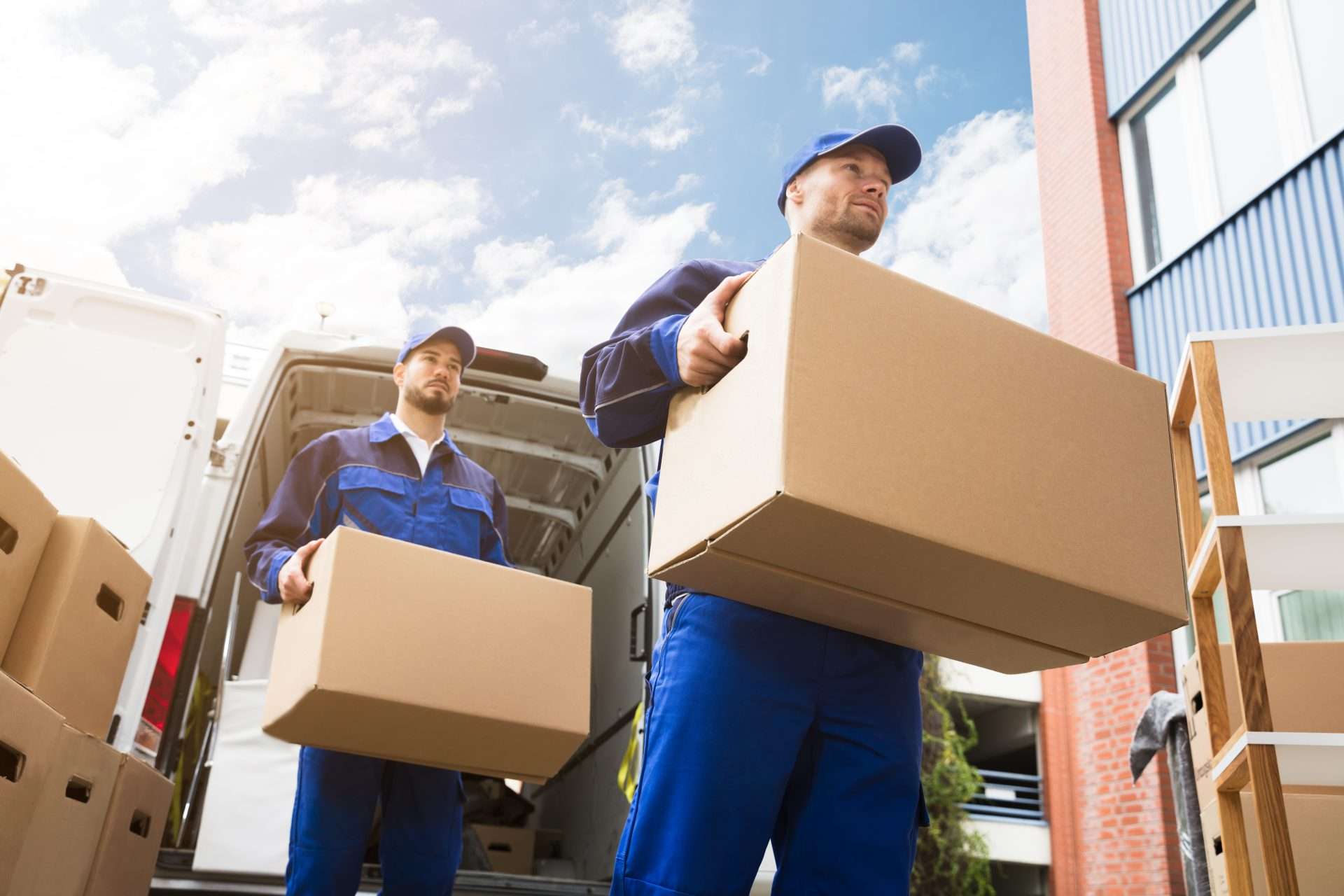 Two movers carrying boxes out of a moving truck.
