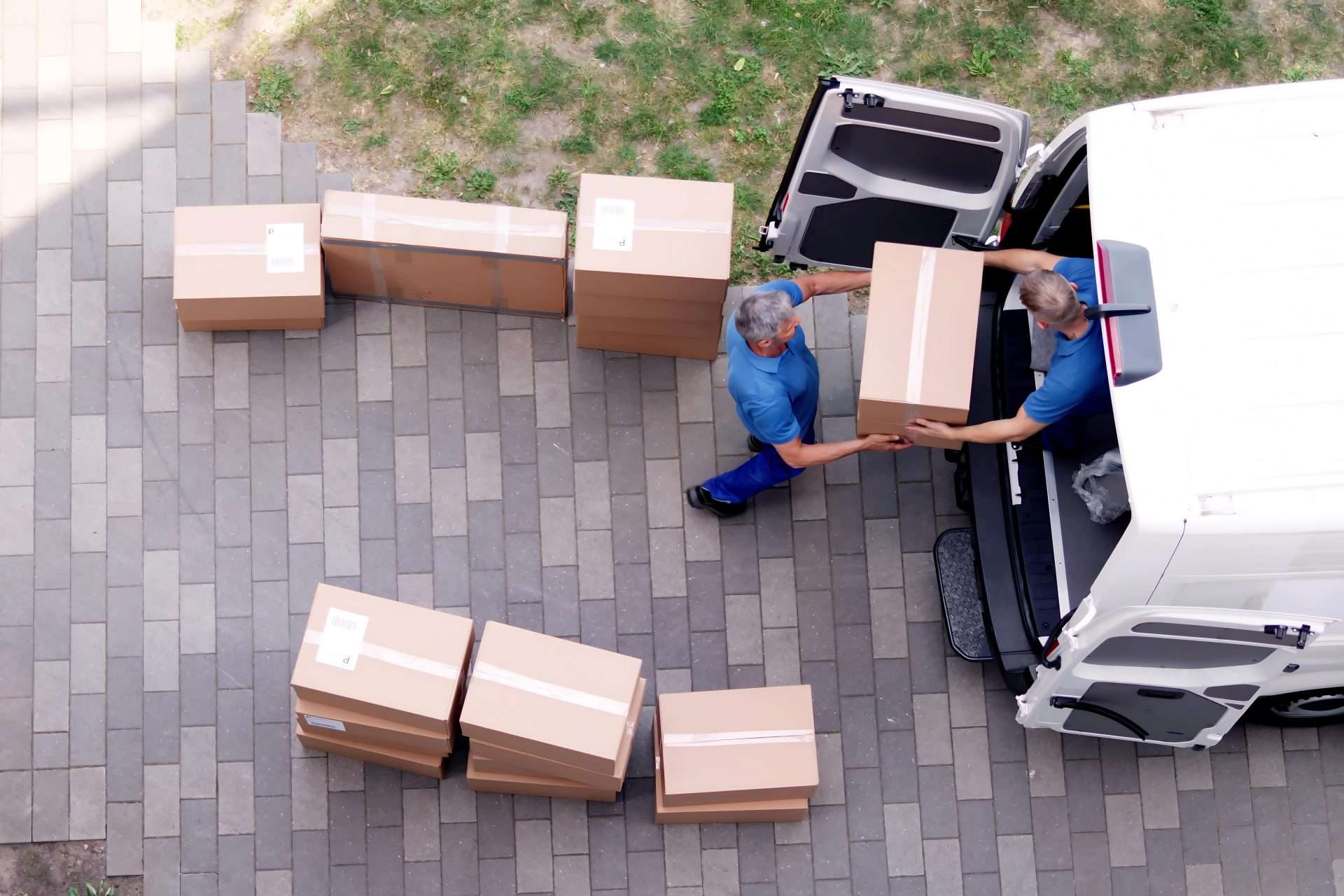 Aerial shot of two movers loading boxes into the back of a white moving van.