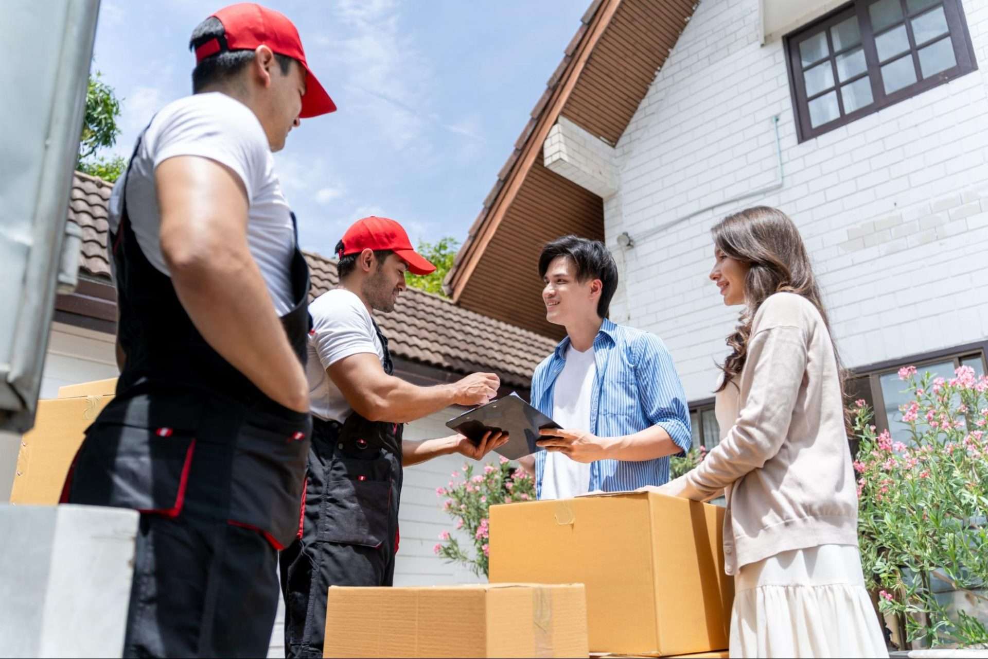 Young couple and two Clinton movers talking, smiling, and signing papers.
