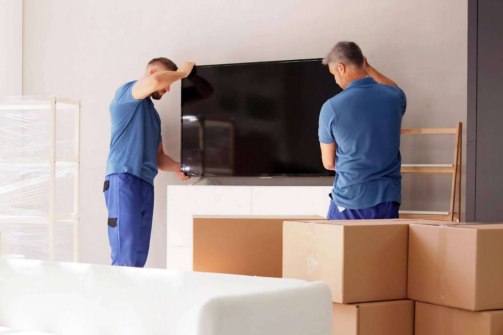two Athol movers removing a television from a TV stand