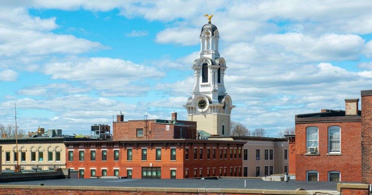 Historic clock tower rising above downtown Lawrence MA with brick mill buildings in view, ideal for those moving to Lawrence and looking for local charm with Mass Bay Movers.
