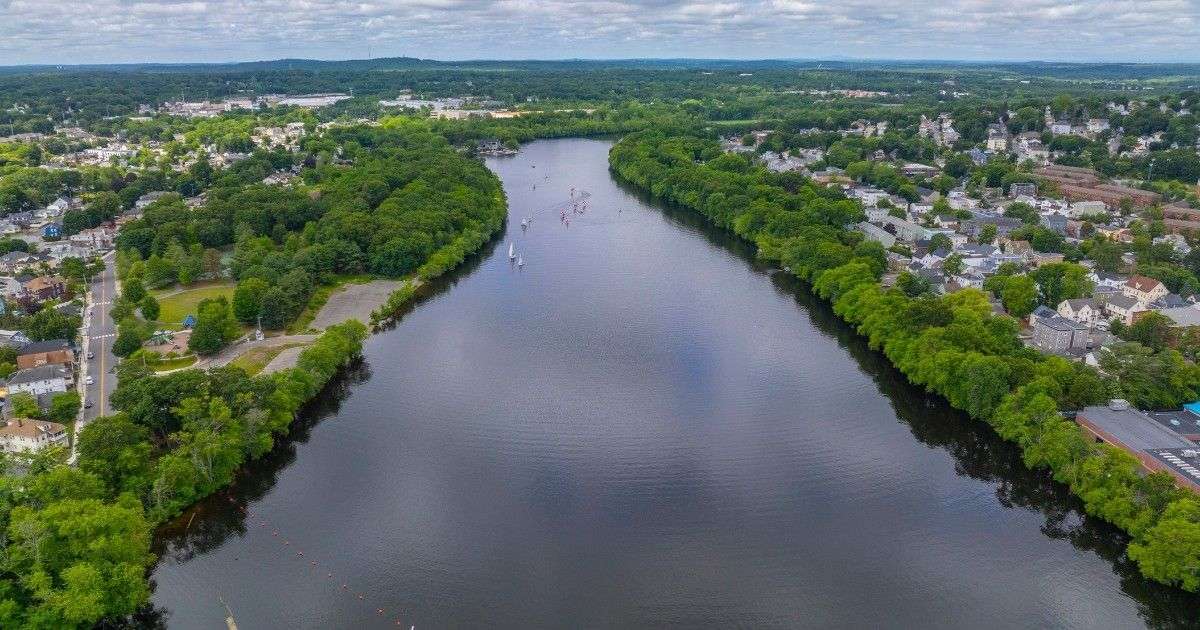 Aerial view of the Merrimack River running through Lawrence MA with sailboats on the water, a peaceful scene for anyone considering living in Lawrence and relocating with Mass Bay Movers.